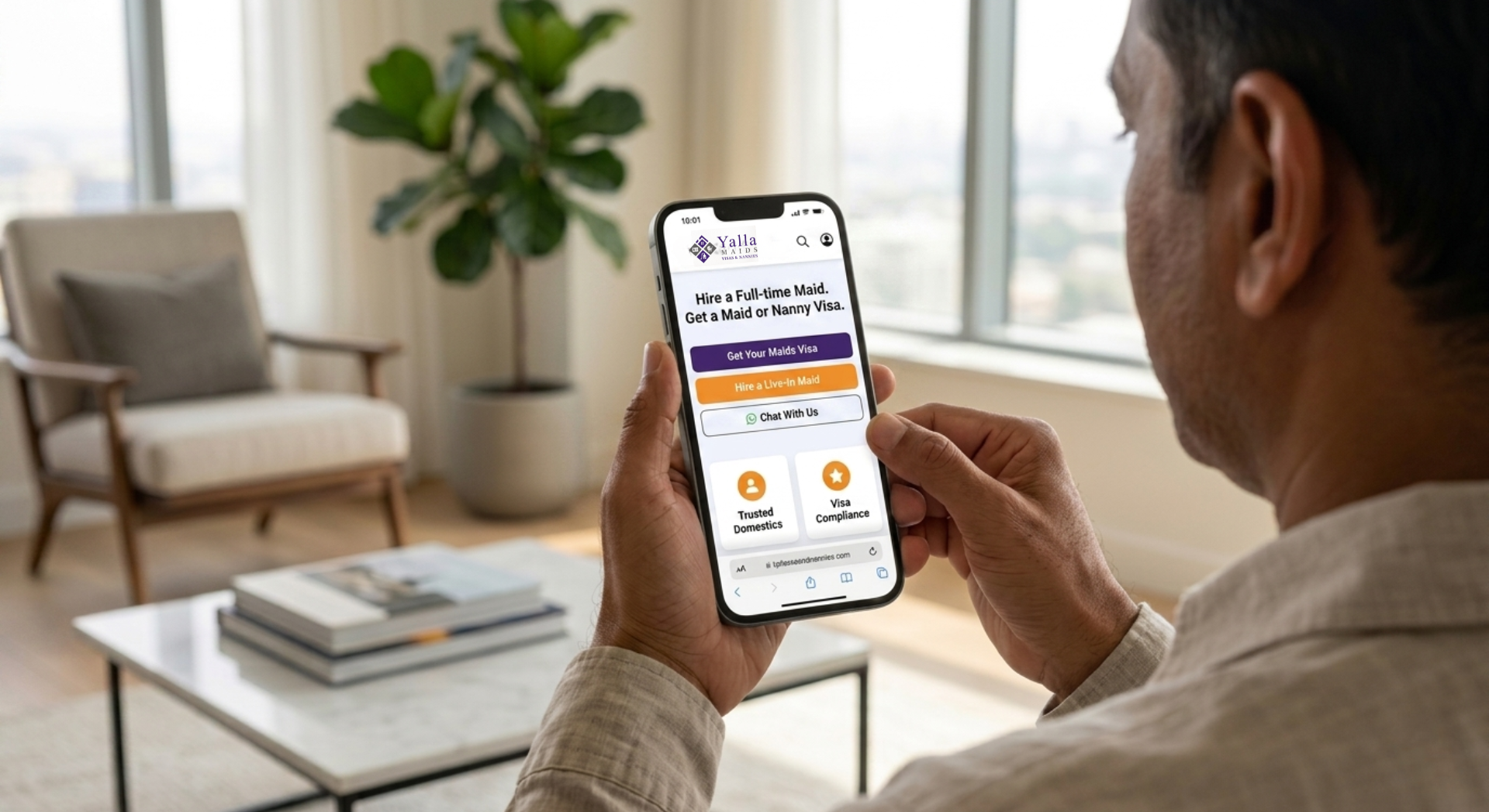 Man using a smartphone at home to hire a maid in Dubai through an online agency platform.