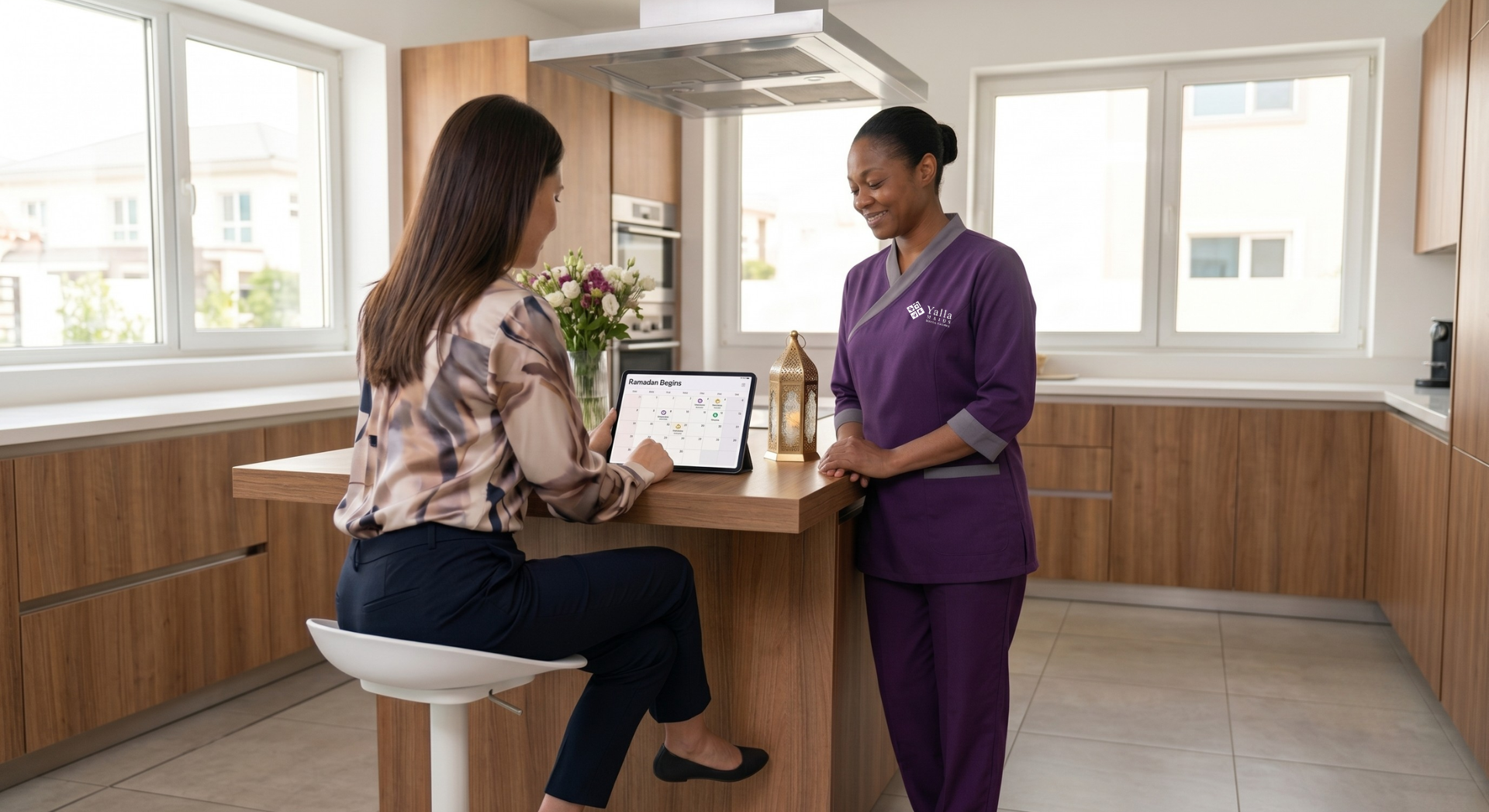 Live in maid Dubai discussing Ramadan and festive season household planning with a family member in a modern kitchen, reviewing schedules on a tablet.