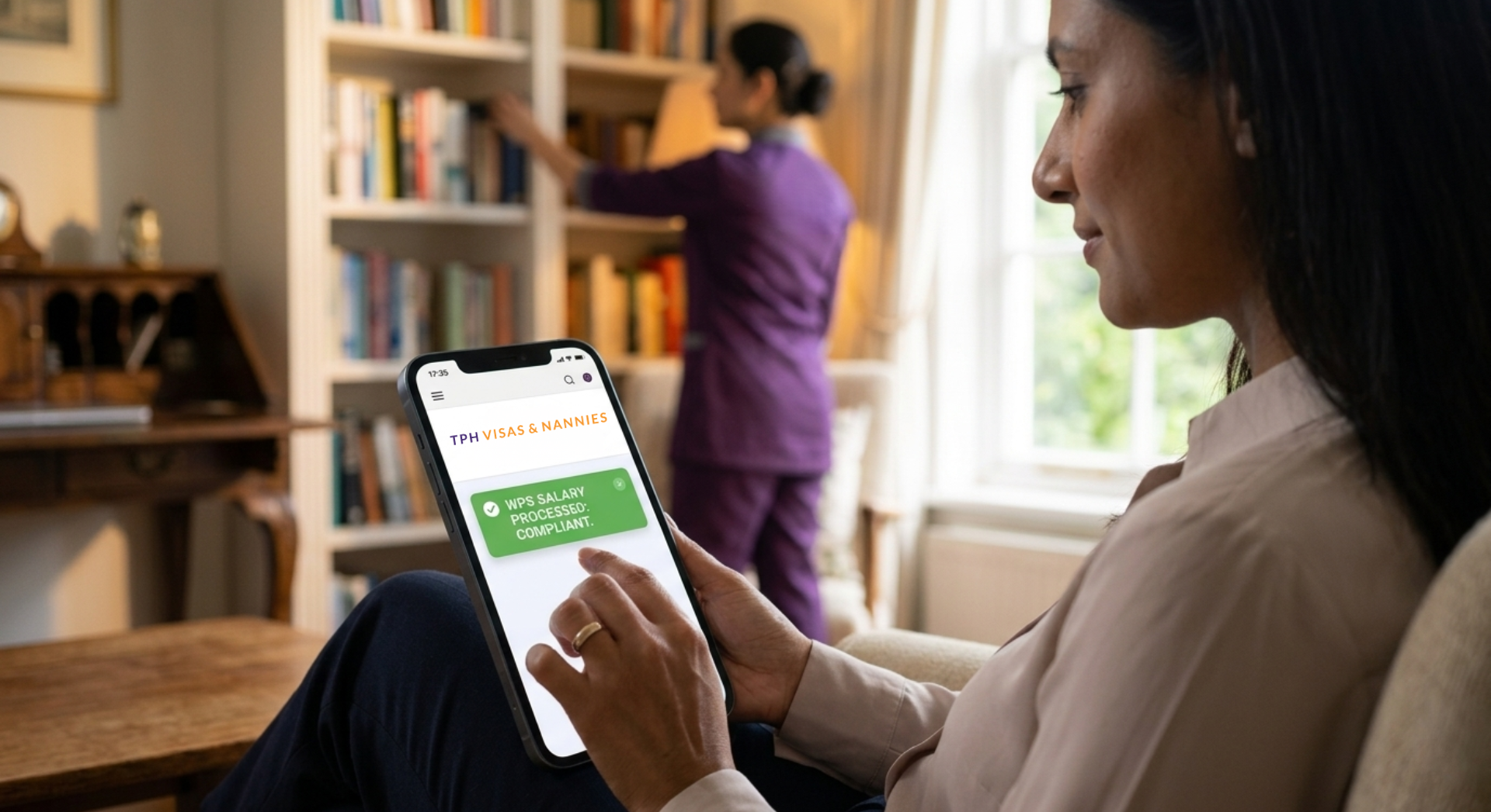 Woman checking WPS compliance on phone for maid visa in Dubai while maid works in background